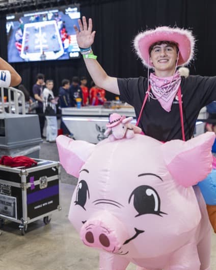 Henry Kehoe, Chief Marketing Officer of Scoutly, at a robotics event in a pink cowboy hat and inflatable pig costume